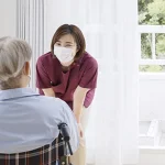 車椅子の患者さんの話を聞く看護師