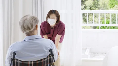 車椅子の患者さんの話を聞く看護師
