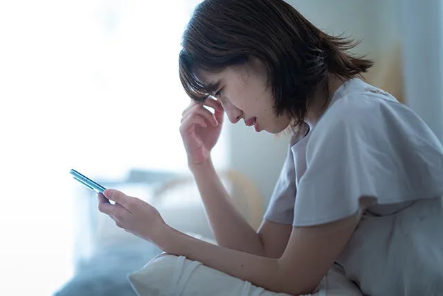 スマホを見て憂鬱な女性