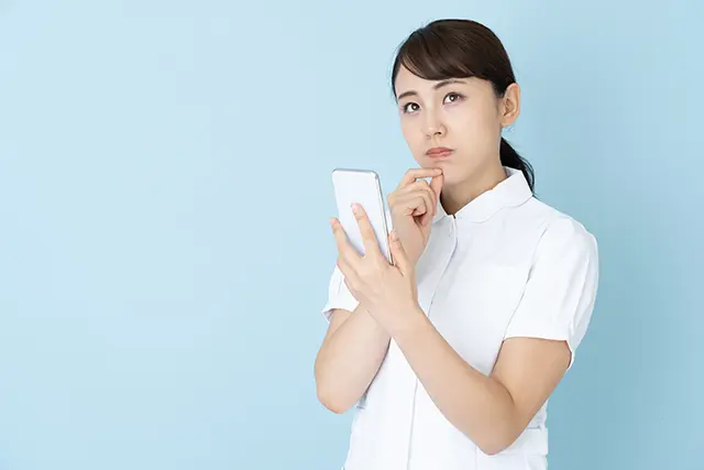 スマホを手に考える看護師